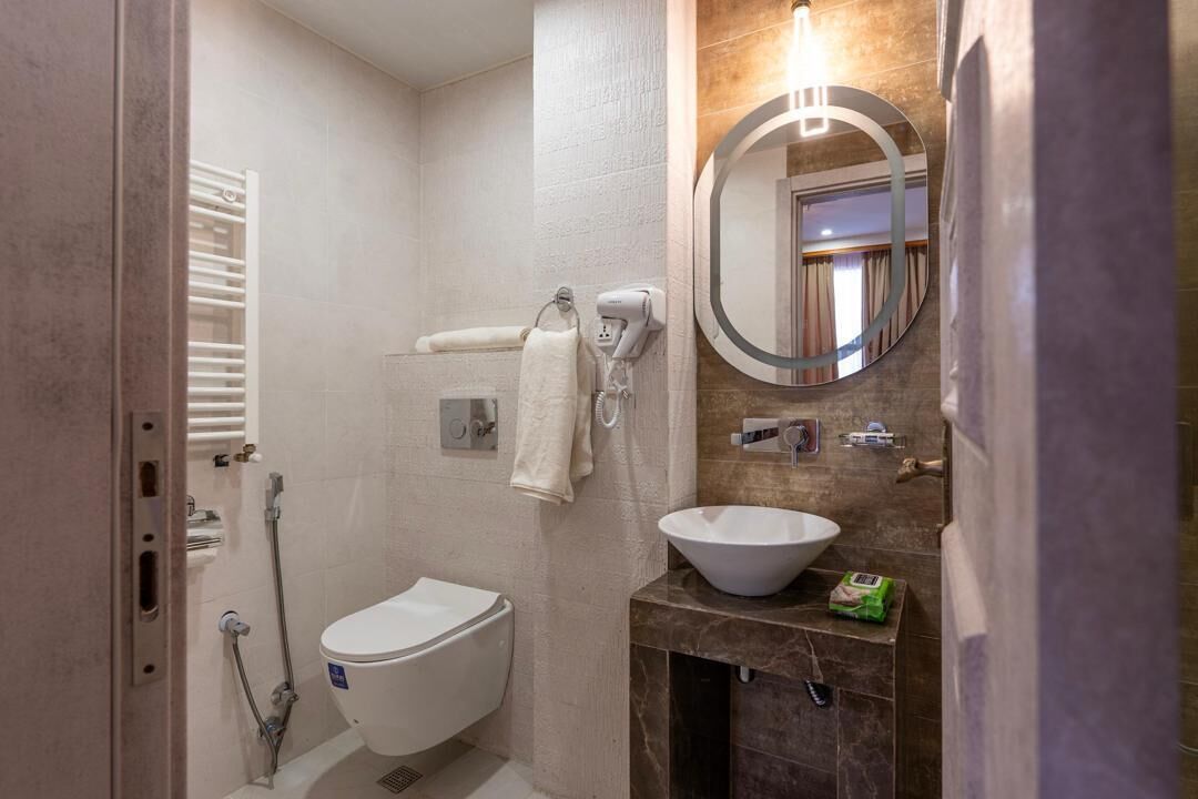 Ein Badezimmer mit Toilette, Waschbecken, Handtuchhalter, Spiegel und Dusche.
