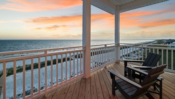A wooden deck with a railing overlooking a beach at sunset. - Large Luxury Beach House with Pool (Port St. Joe)