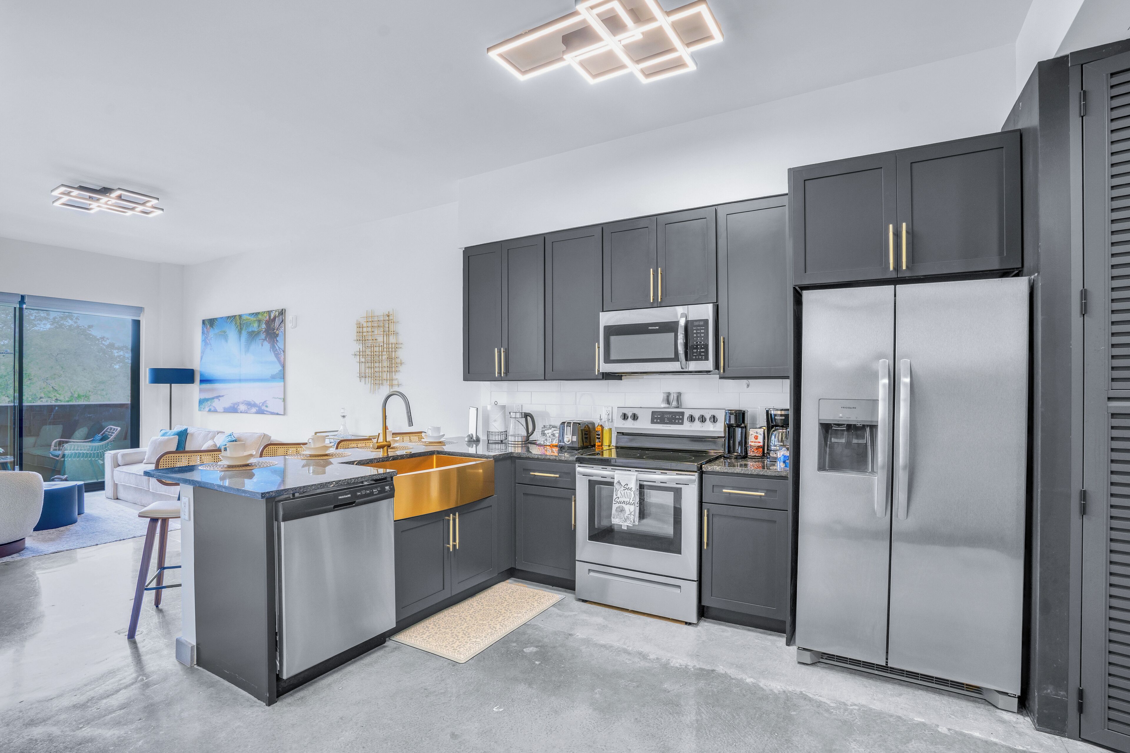 A modern kitchen with dark cabinets, stainless steel appliances, and a large island with a sink.