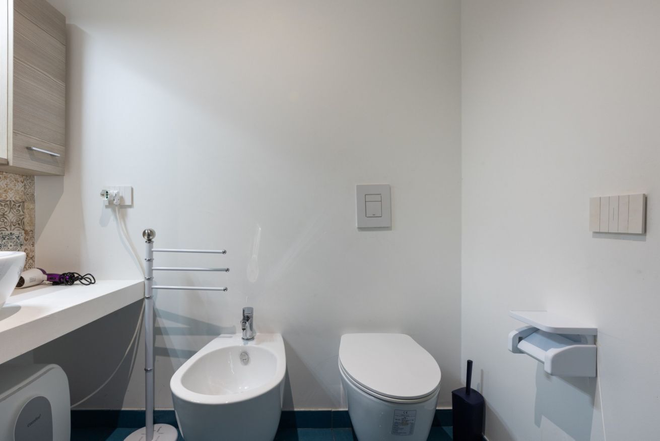 A bathroom with a bidet, toilet, and a towel rack.