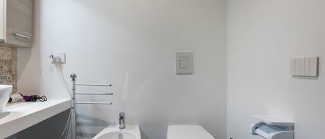 A bathroom with a bidet, toilet, and a towel rack.