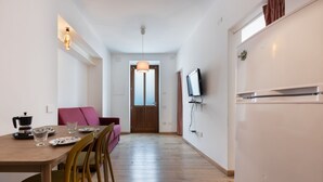 Eine moderne Küche mit Essbereich, Holzboden und einem an der Wand befestigten Fernseher.