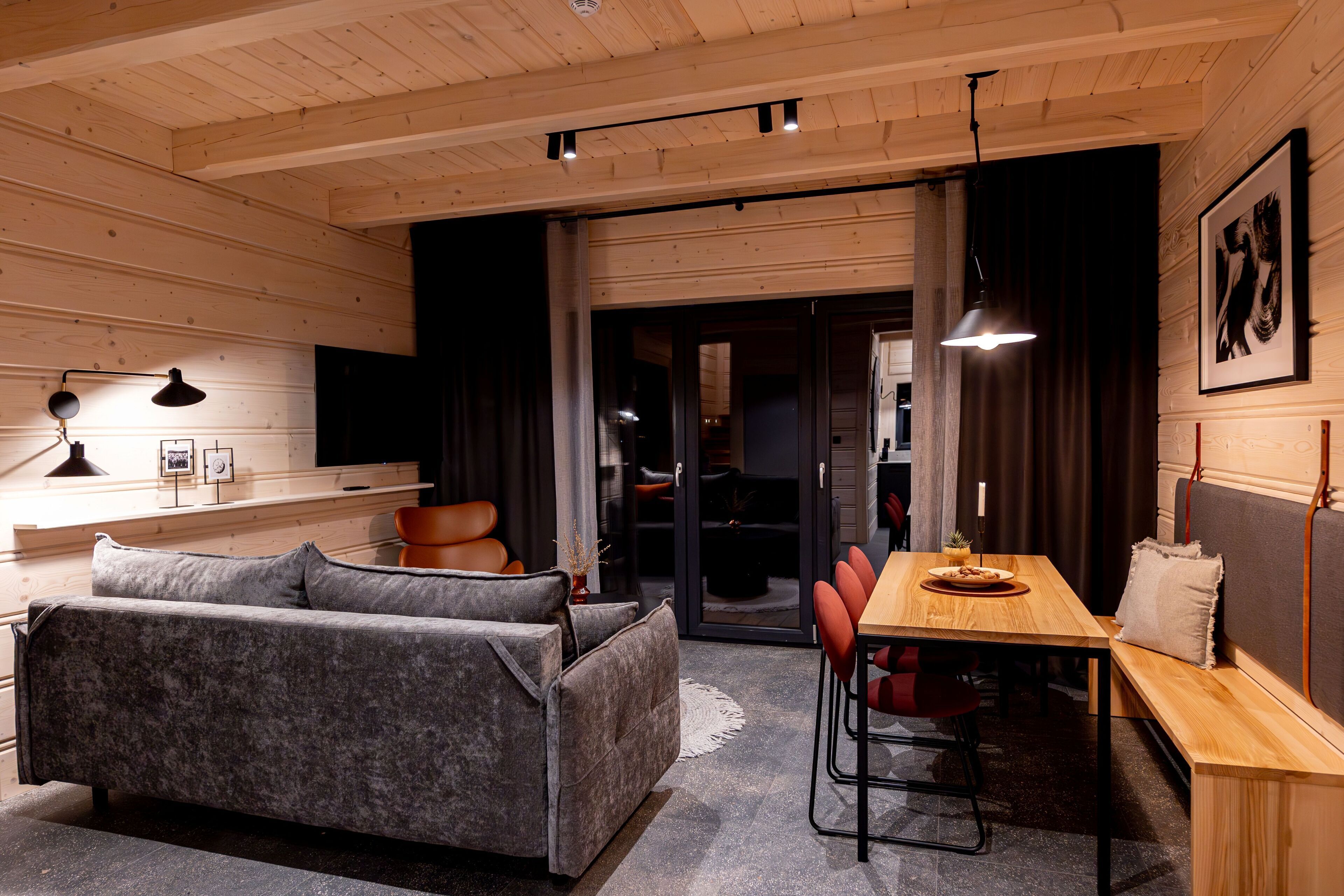 Un interno moderno con soffitto in legno, un divano, un tavolo da pranzo con sedie e una TV a parete.