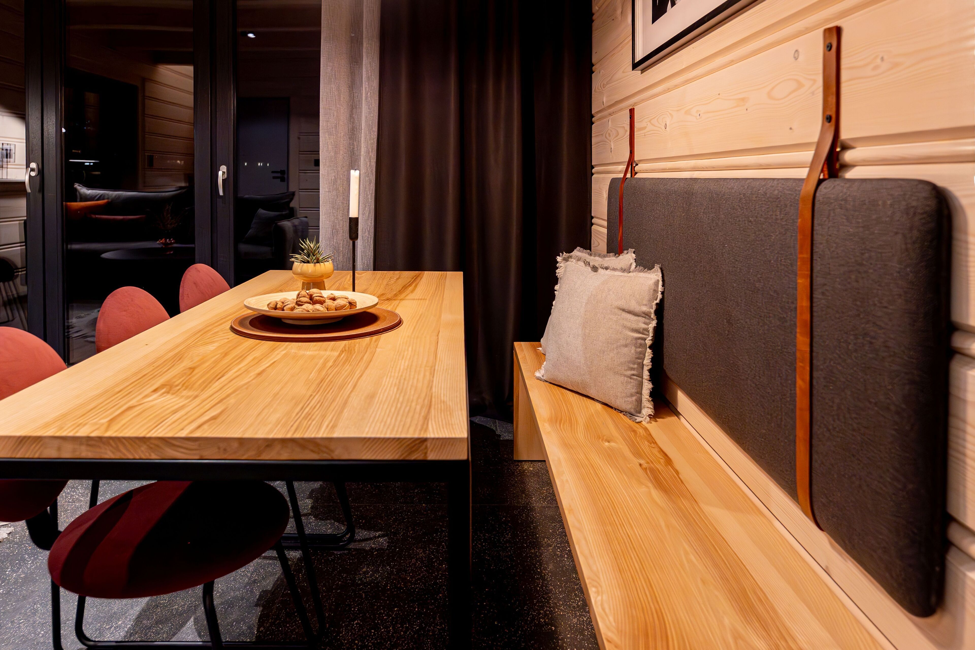 A wooden dining table with a plate of food, red chairs, and a bench with a cushion.