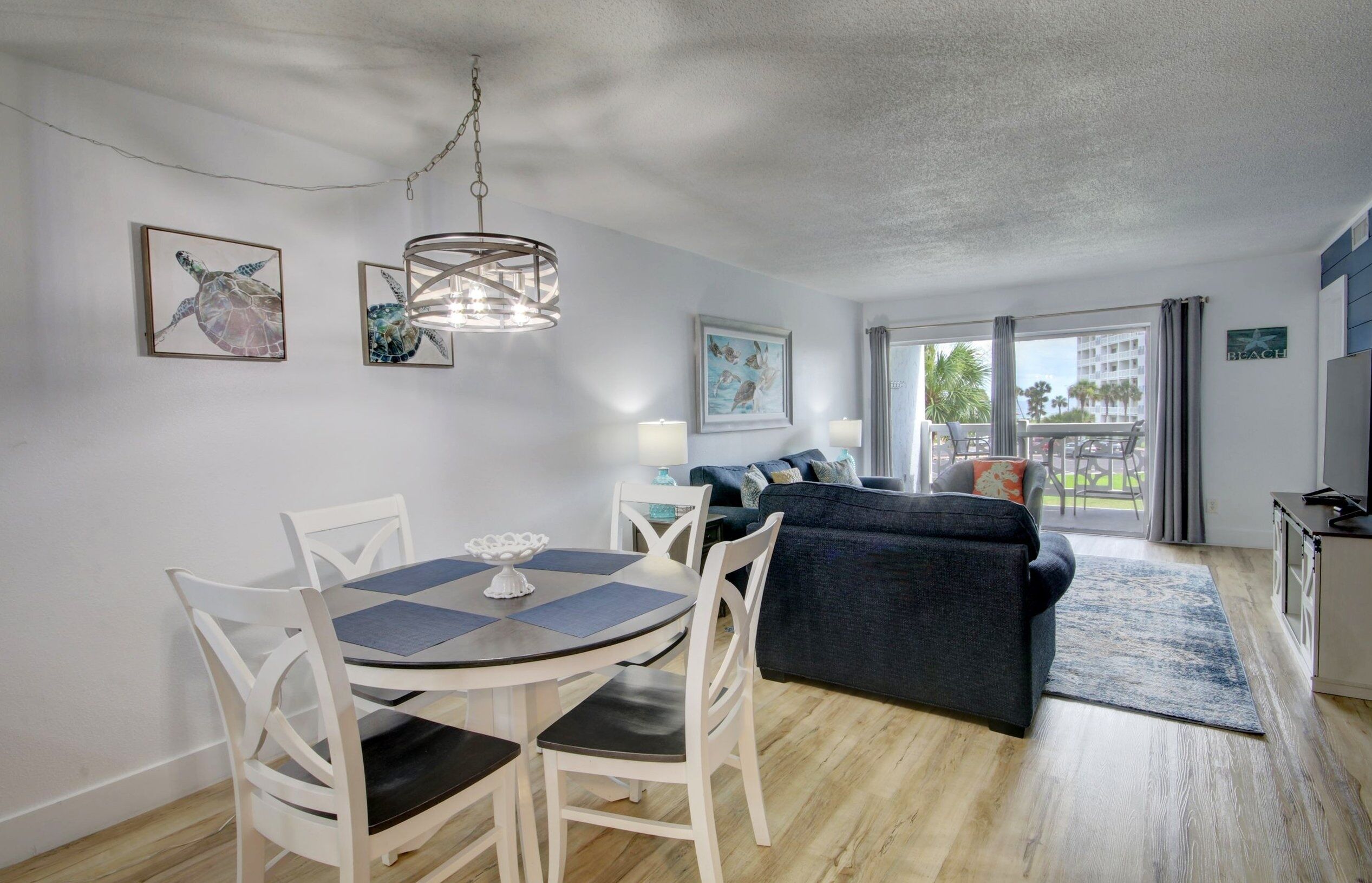 Una sala de estar moderna con comedor, un sofá azul oscuro y vistas al exterior.