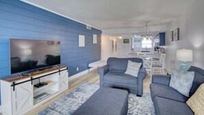 A living room with a large flat-screen TV, grey sofas, and a wooden entertainment unit.