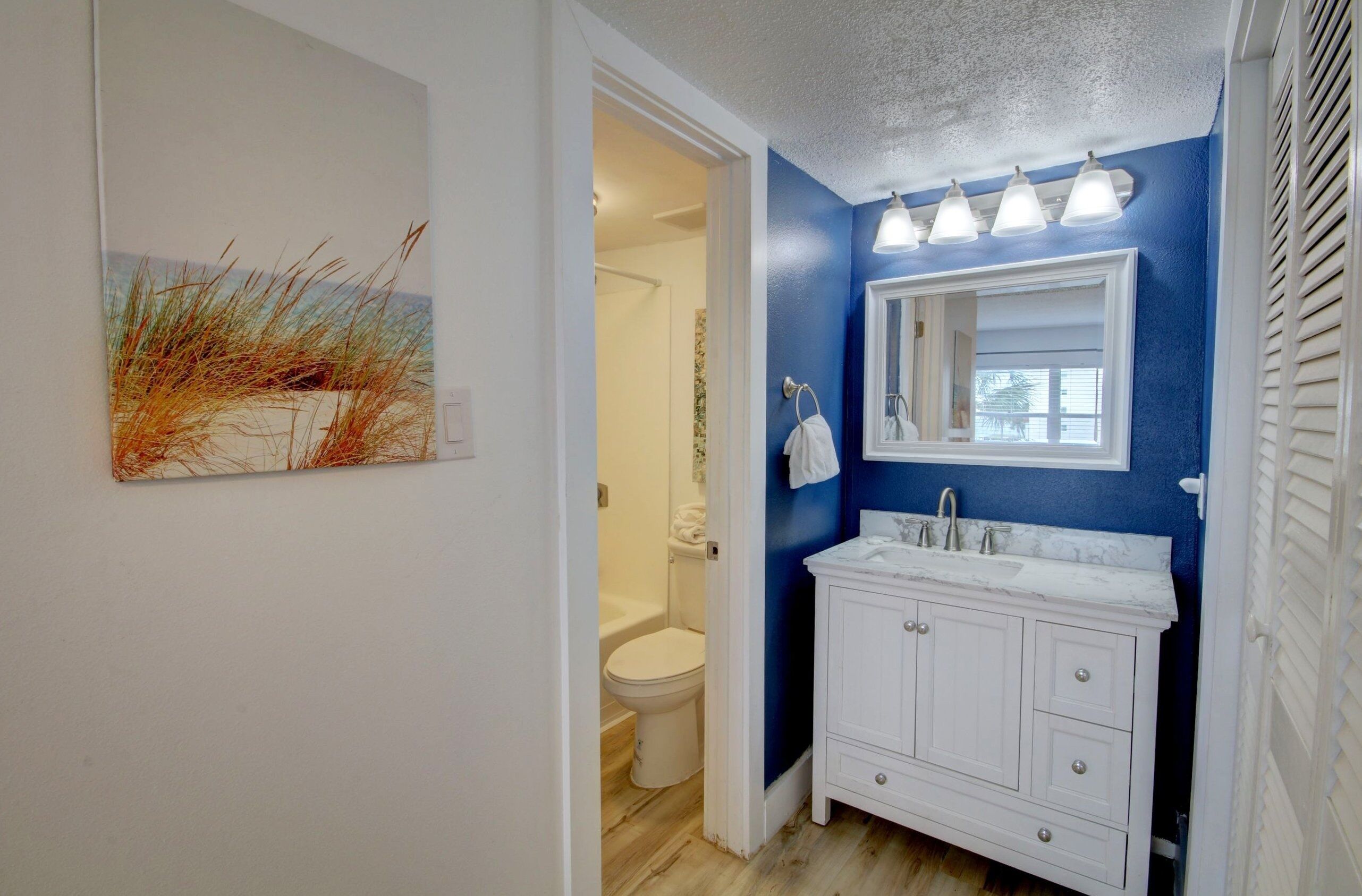 Une salle de bain avec un meuble-lavabo blanc, un miroir et un mur d’accent bleu.