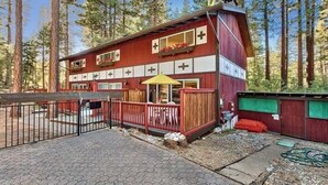 Un edificio rojo y blanco con un balcón y un paraguas amarillo, rodeado de árboles.