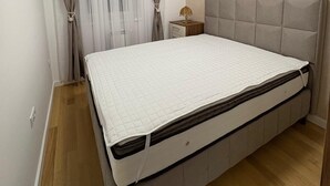 A bedroom with a bed, curtains, a bedside table, and a ceiling light. - I&I Apartments 36 (Kragujevac)
