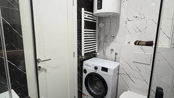 A compact bathroom with a washing machine, toilet, and a water heater.