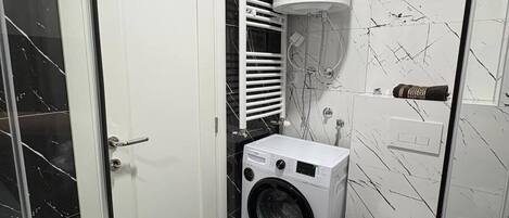 A compact bathroom with a washing machine, toilet, and a water heater.