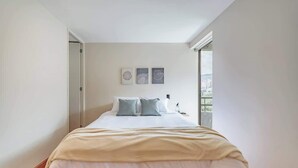 Une chambre à coucher avec un lit, une table de chevet et une fenêtre.