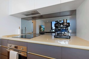 A modern kitchen with a built-in espresso machine, a large island, and a view of the outdoors.