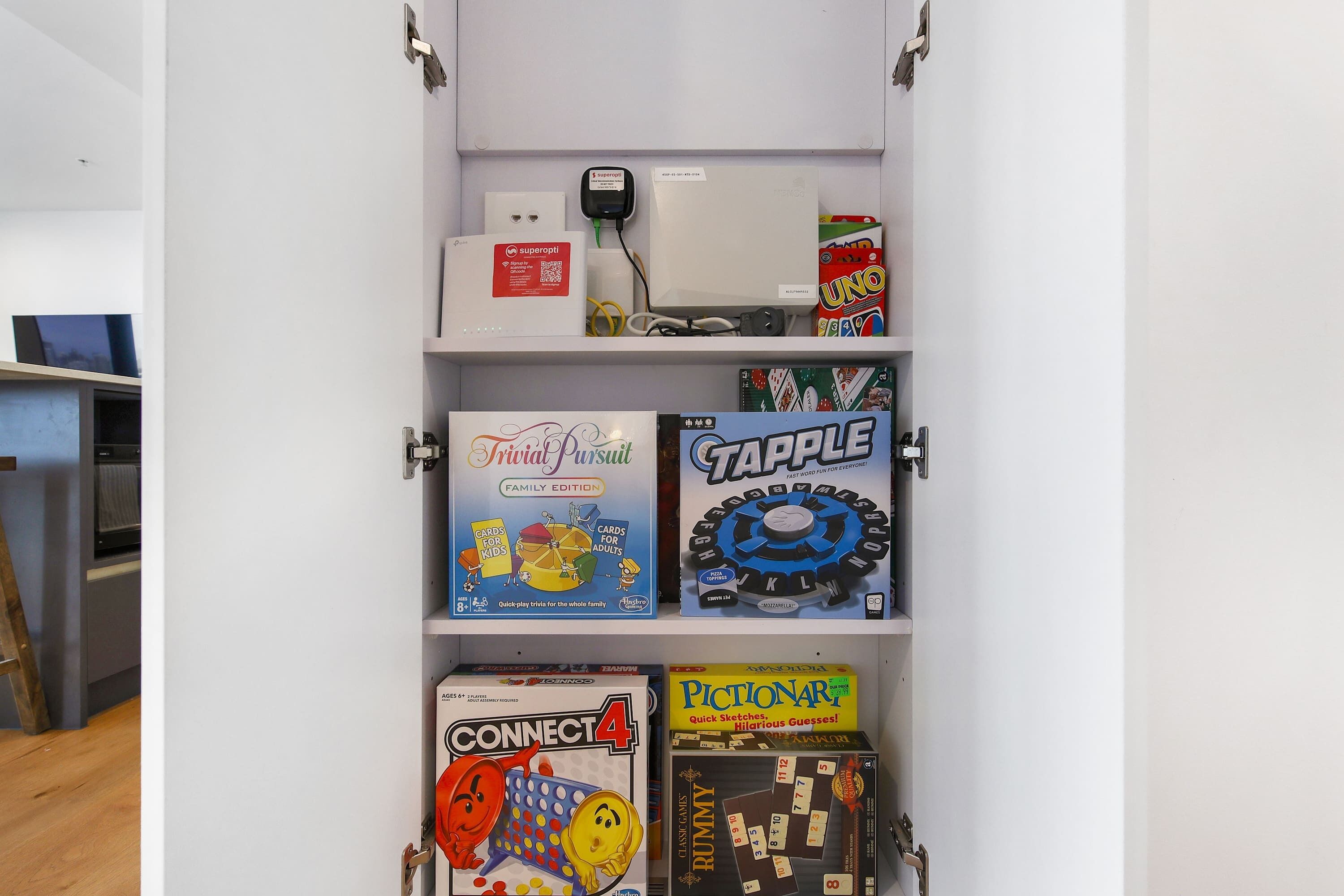 Ein Regal mit verschiedenen Gesellschaftsspielen, darunter Trivia Pursuit, Tapple, Connect 4 und Pictionary.