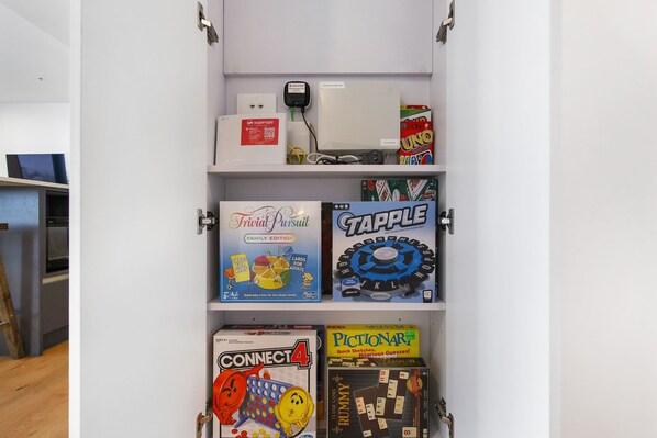 Une étagère contenant divers jeux de société, notamment Trivia Pursuit, Tapple, Connect 4 et Pictionary.