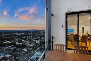 A balcony with a city view, a dining area with chairs, and a sliding glass door.