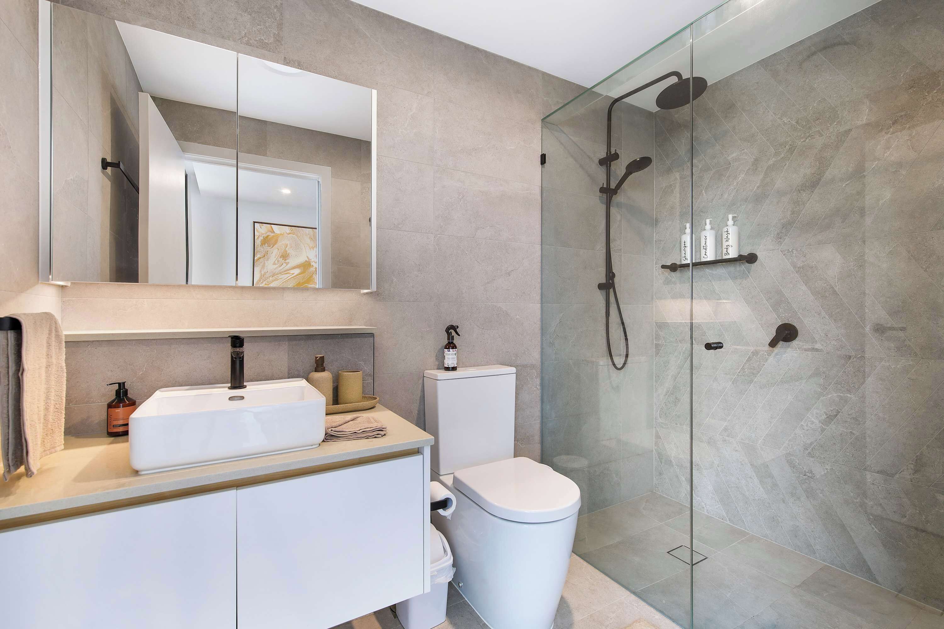A modern bathroom with a glass-enclosed shower, a white sink, and a toilet.