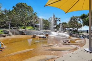 A water feature with a fountain, seating areas, and a yellow umbrella.
