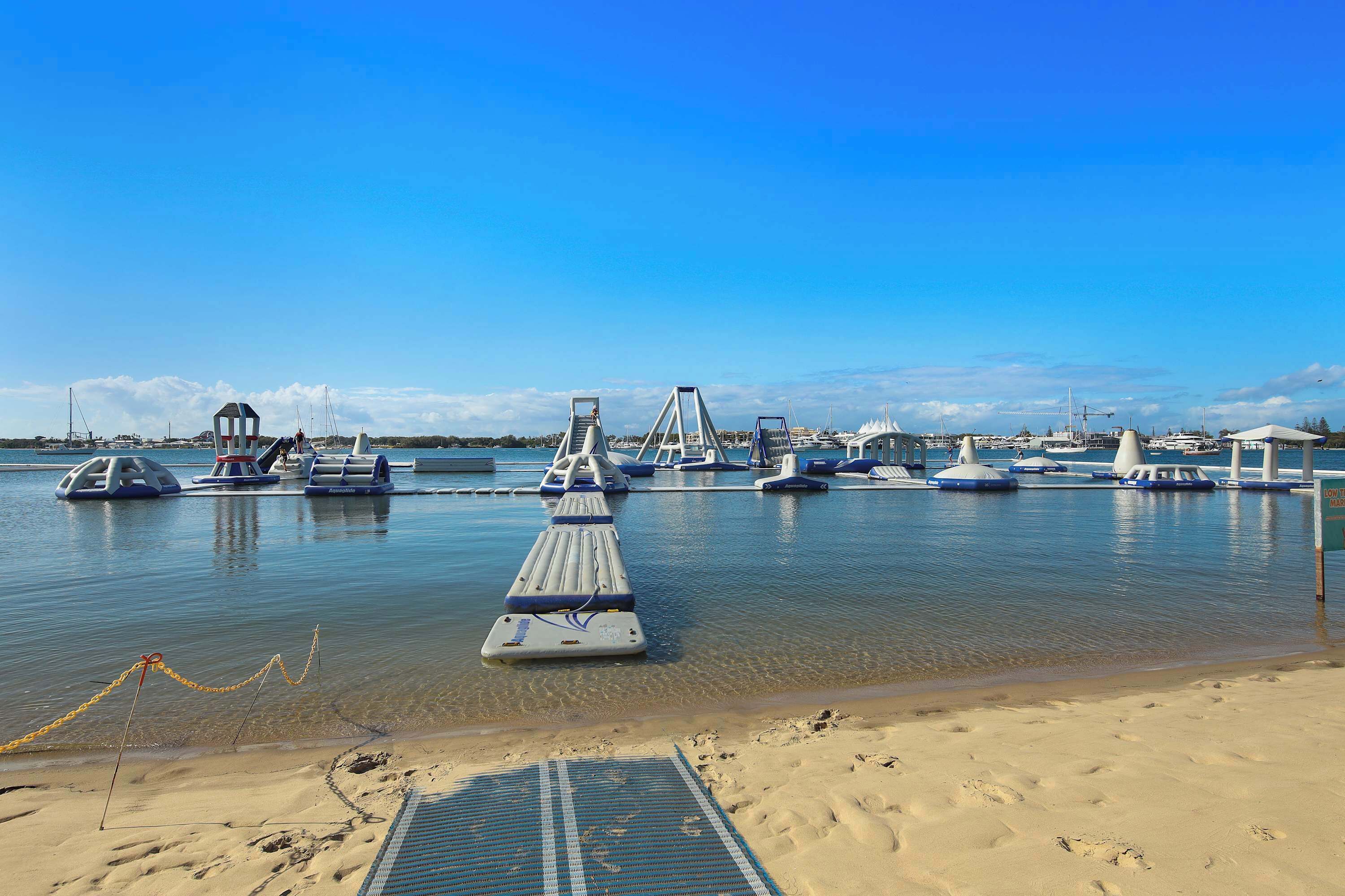 A marina with boats, a jetty, and a sandy beach.