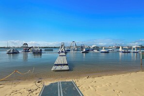 A marina with boats, a jetty, and a sandy beach.