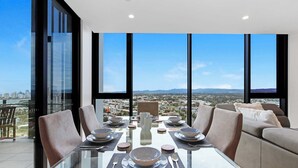 Comedor con mesa de vidrio, sillas y vista a la ciudad.