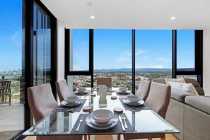 A dining area with a glass table, chairs, and a city view.