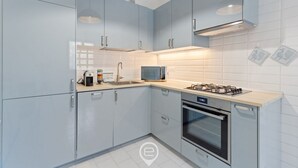 Een moderne keuken met lichtblauwe kastjes, een gasfornuis, een magnetron en een inbouwoven.