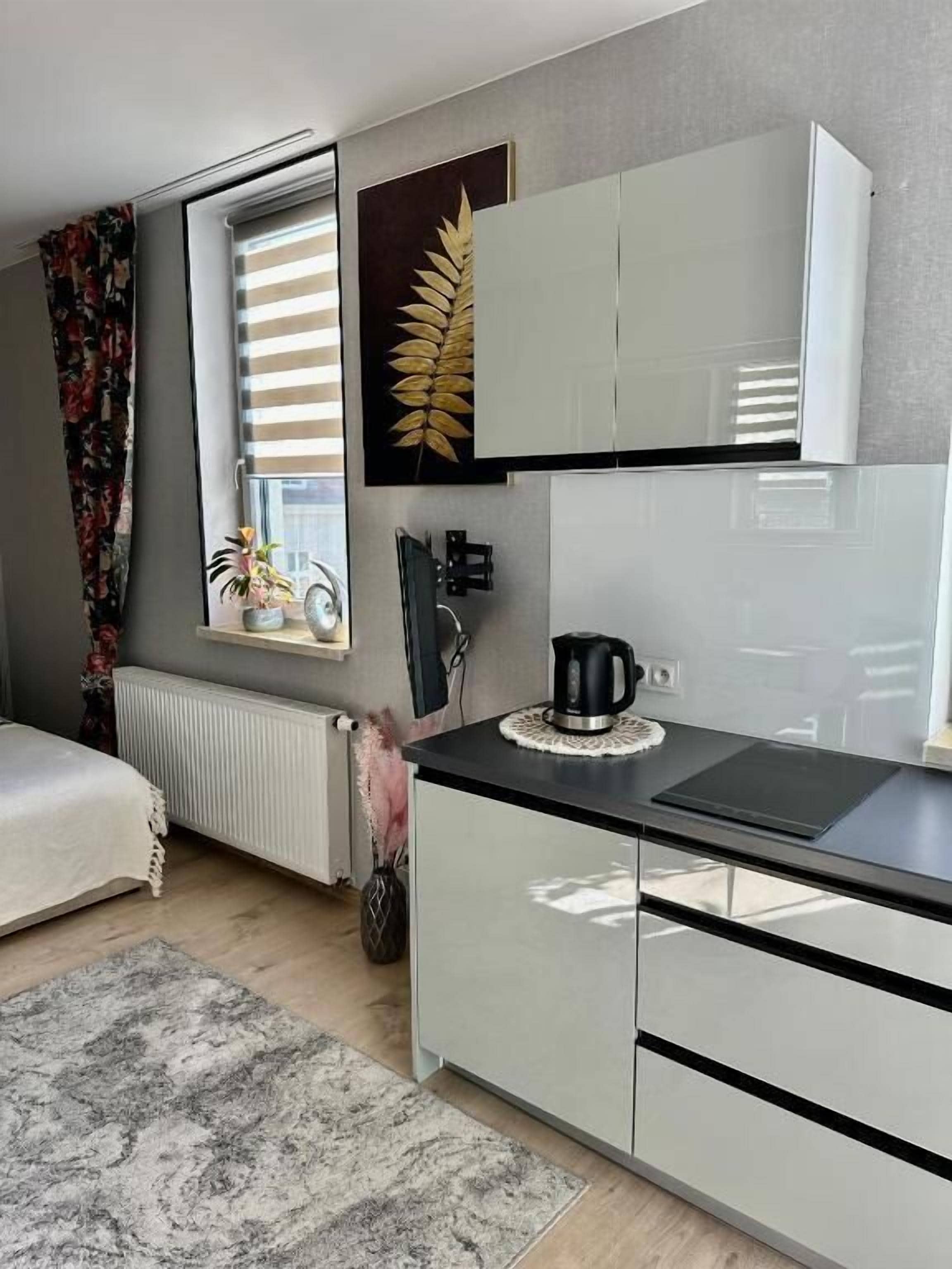 Una cucina moderna con mobili bianchi, un piano di lavoro nero e una finestra con persiane.
