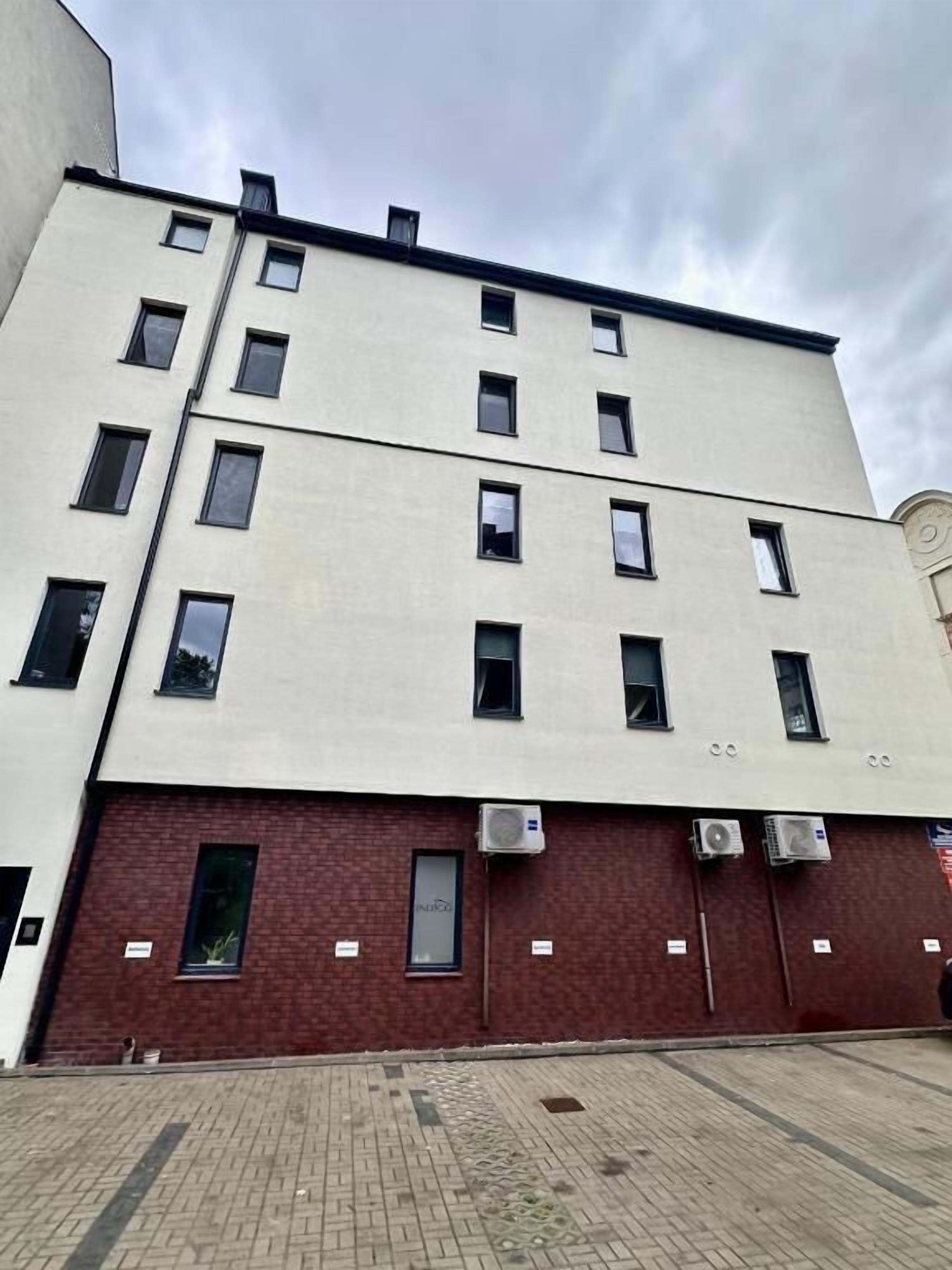 A multi-story building with a flat facade, multiple windows, and air conditioning units.
