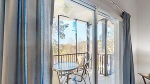 A room with a sliding glass door leading to an outdoor balcony with a table and chairs. - Lakefront Condo w/ 6 Heated Pools | Near Disney! (Davenport)