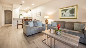 A living room with a grey sofa set, a wooden coffee table, and a painting on the wall. - Lakefront Condo w/ 6 Heated Pools | Near Disney! (Davenport)