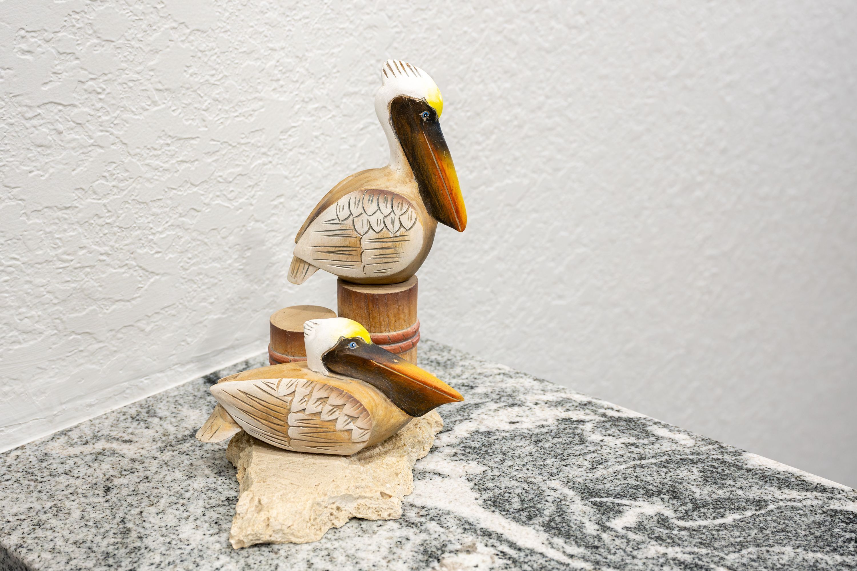 Una escultura de madera de un pájaro sobre una superficie rugosa.