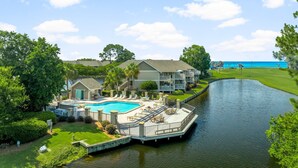 A resort with a swimming pool, a dock, and a view of the ocean. - Golf Cart ~ Golf Course & Lake Views (Miramar Beach)