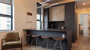 A modern kitchen with a central island, bar stools, and a chair.