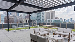 A rooftop patio with outdoor seating, a pergola, and a city skyline view.
