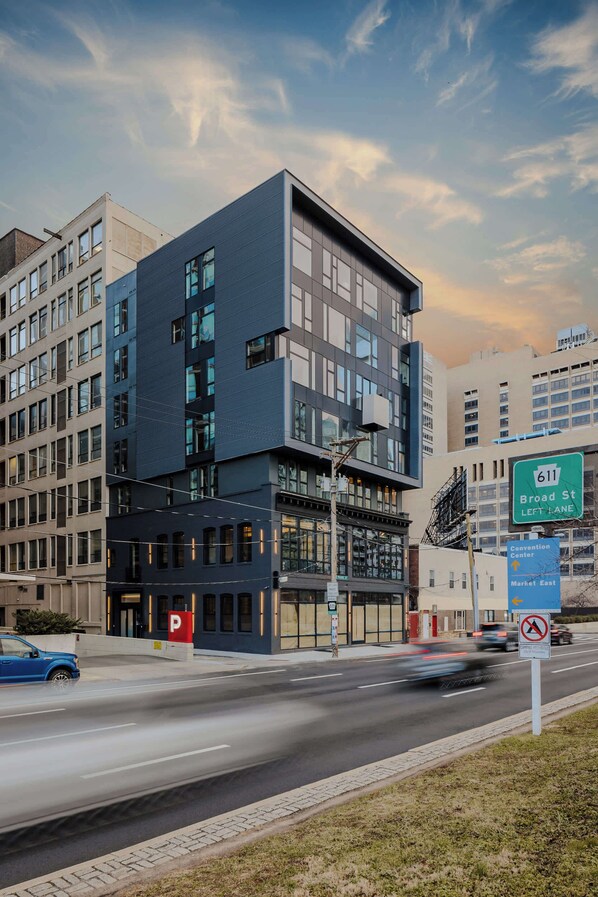 A modern building with multiple floors, large windows, and a parking sign indicating a parking area.
