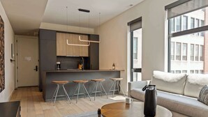 A modern living room with a sofa, a coffee table, and a bar area with stools.