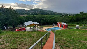 Un quartier résidentiel avec une piscine, une voiture rouge et un petit bâtiment doté d’un toit rouge.