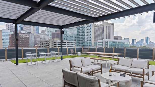 A rooftop patio with outdoor seating, a pergola, and a city skyline view.