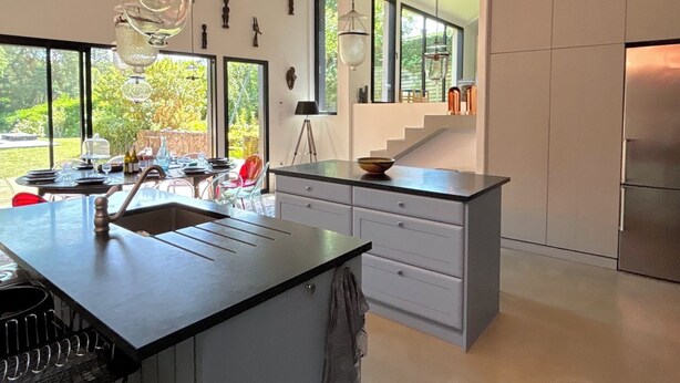 A modern kitchen with a central island, large windows, and a view of the outdoors. - Villa Oscar (Les Mesnuls)