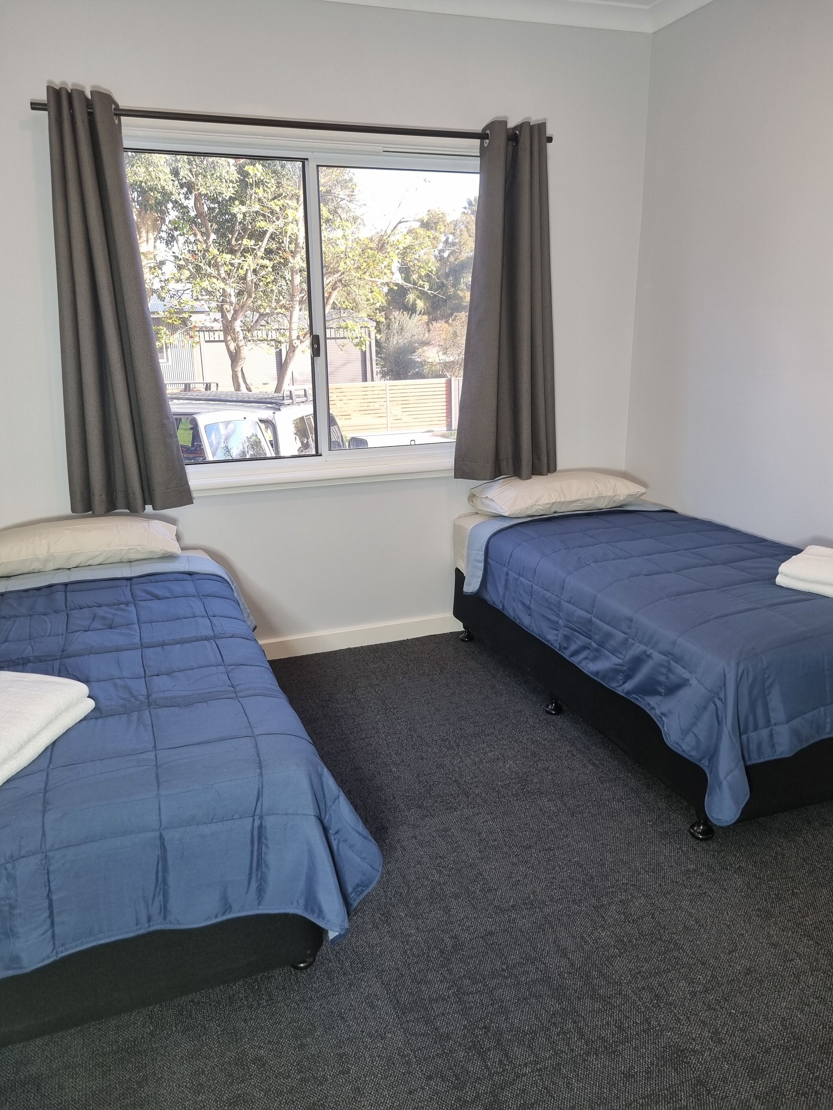 Une chambre avec deux lits, une fenêtre avec des rideaux et une vue sur l’extérieur.