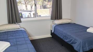 Une chambre avec deux lits, une fenêtre avec des rideaux et une vue sur l’extérieur.