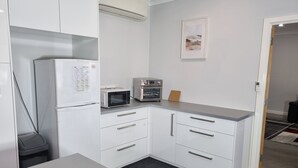 A compact kitchen with white cabinets, a microwave, a toaster, and a refrigerator. - City View 3 Bedrooms & Work from Home Office, close to airport (Koongamia)