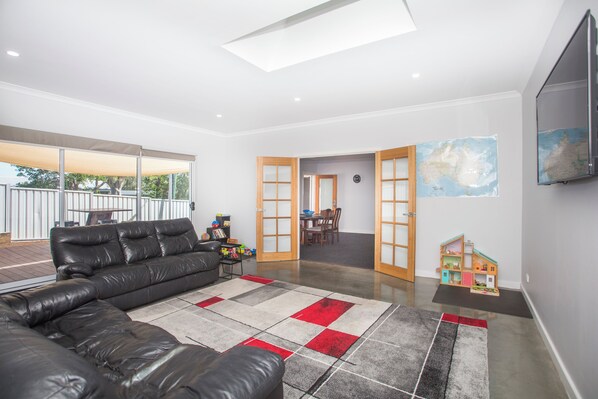 Living room with view to outdoor deck, and dining areas