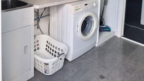 A compact laundry area with a washing machine, a sink, and a drying rack. - City View 3 Bedrooms & Work from Home Office, close to airport (Koongamia)