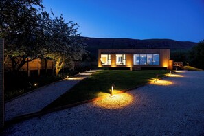 Una casa moderna con camino de grava y un interior bien iluminado.