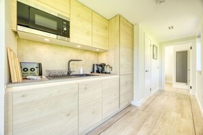 A modern kitchen with wooden cabinets, a stainless steel microwave, and a sink. - Retreat to the Campsies (Lennoxtown)