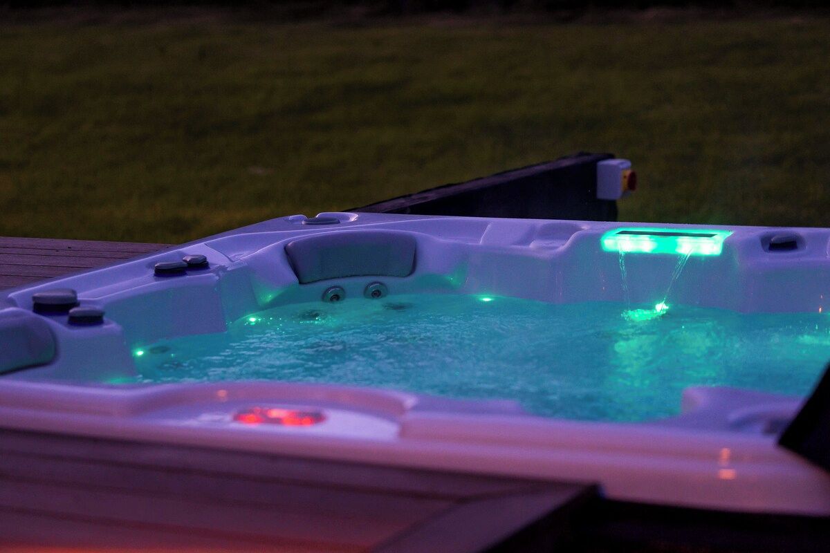 A hot tub with illuminated controls and a wooden deck.