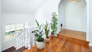 Une pièce spacieuse avec un escalier en bois, des murs blancs et de grandes fenêtres.