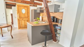 Une cuisine moderne dotée d’un îlot central, de poutres en bois et d’un coin repas avec une table et des chaises.